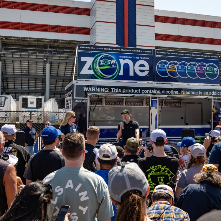 Kyle Bushch speaking in front of a crowd at a a Zone kiosk