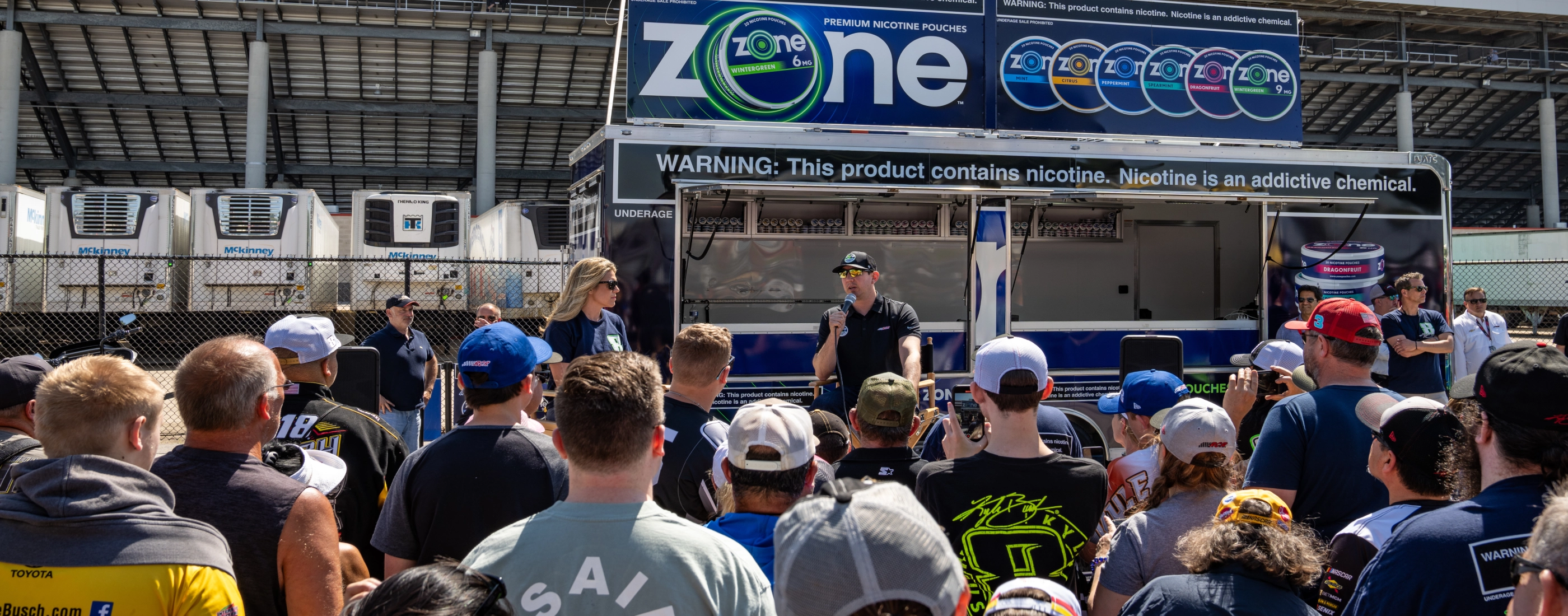 Kyle Bushch speaking in front of a crowd at a a Zone kiosk